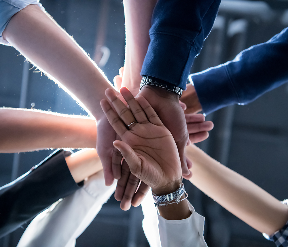 Hands of a business team in a business huddle all stacked for a break.